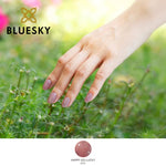Bluesky Nude Pink Happy Go Lucky Gel Polish with fine glitteron models nails against a grass background